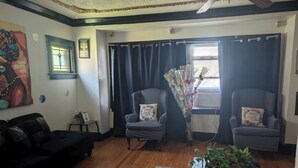 A living room with a black leather sofa, two grey armchairs, a wooden coffee table, and a potted plant. - Step into this spacious-style home (Milwaukee)