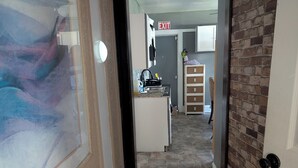 A narrow hallway leading to a kitchen area with a stone floor, a white cabinet, and an exit sign. - Step into this spacious-style home (Milwaukee)