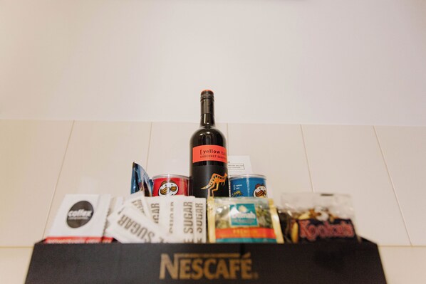 A box labeled Nescafé containing various items including a bottle of yellowtail wine, coffee packets, and snacks.