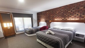 Habitación de hotel con dos camas, una pared de ladrillo, un ventanal grande y una puerta.