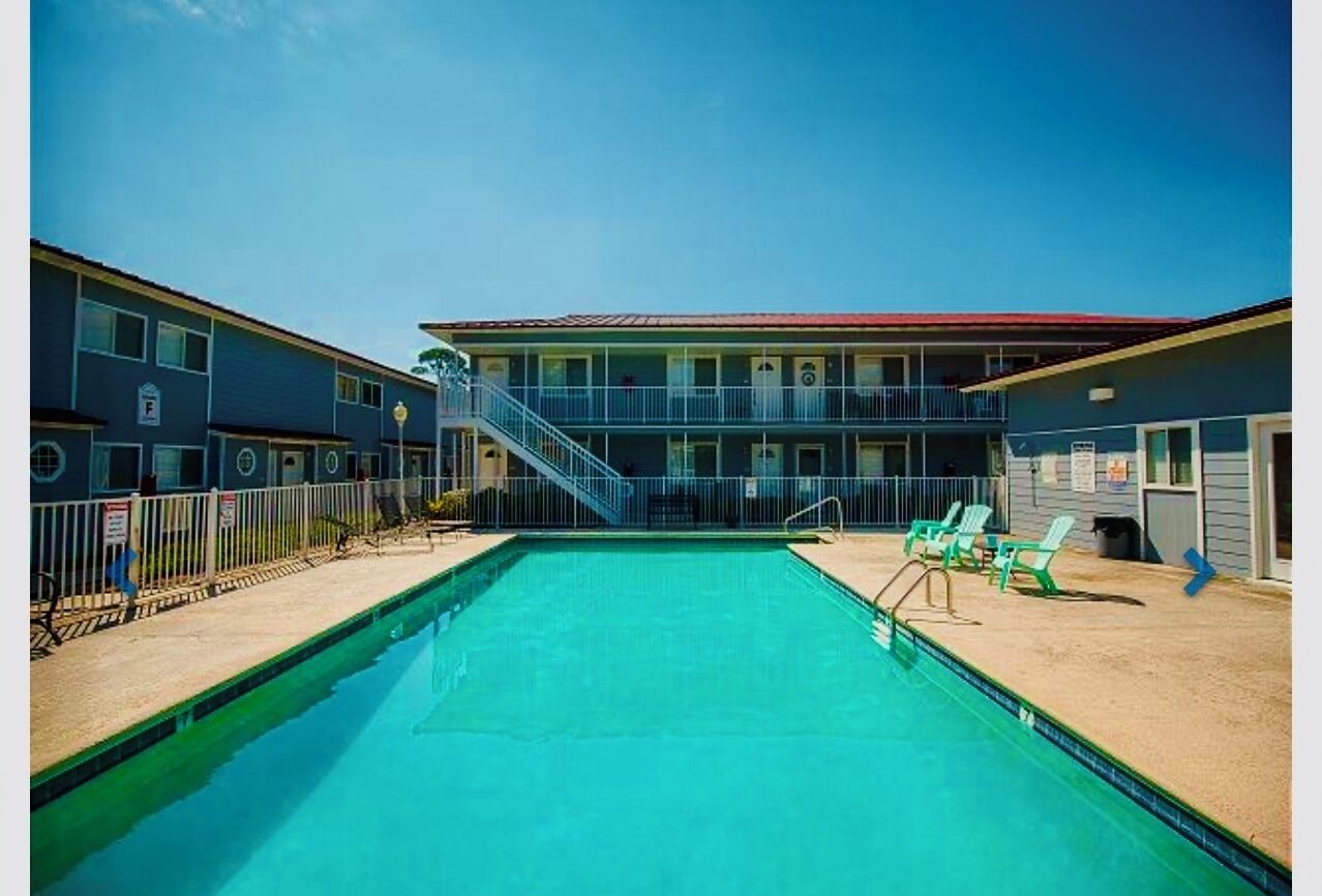 A swimming pool with a staircase leading to a building with multiple balconies.
