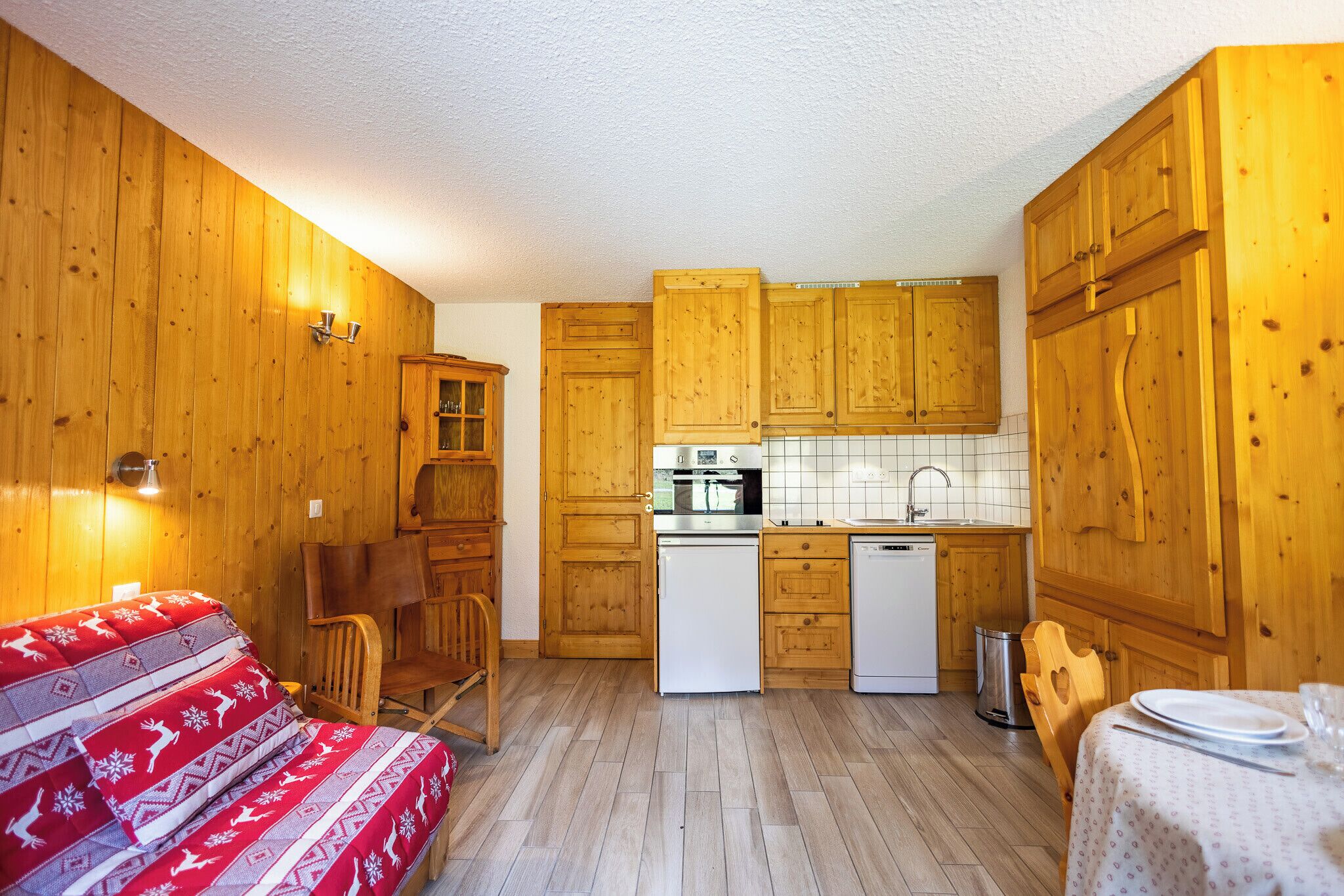 A compact kitchen with wooden cabinets, a white refrigerator, a sink, and a stove.