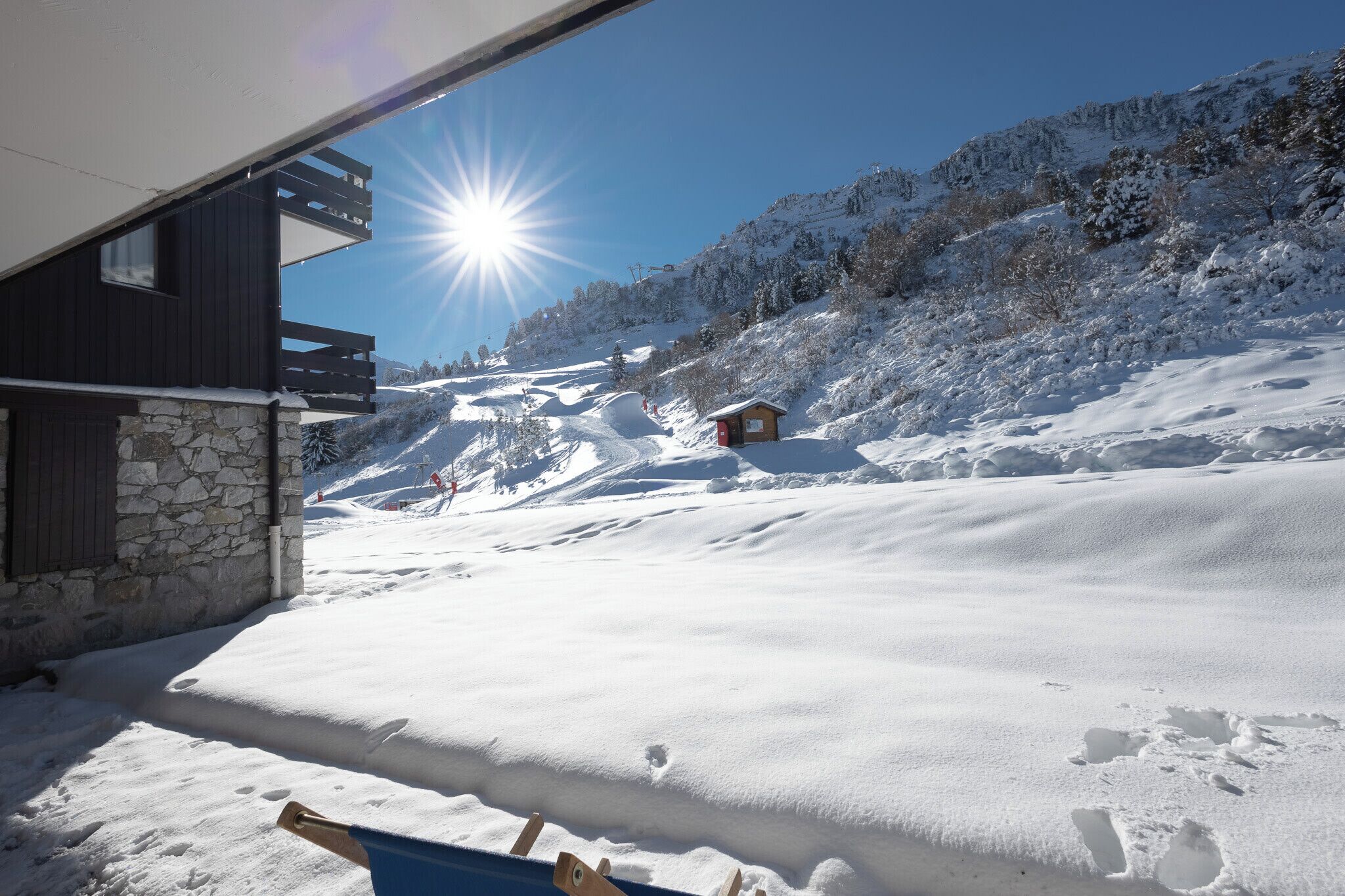 Eine verschneite Berglandschaft mit einem Holzhaus und einer kleinen Hütte in der Ferne.