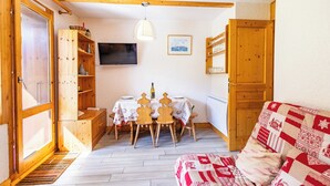 Une pièce chaleureuse avec une table à manger en bois, des chaises, un téléviseur et un canapé.
