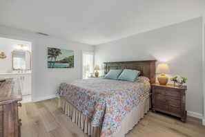 Camera da letto con un letto, abat-jour, comodino, cassettiera, un quadro e una finestra con persiane.