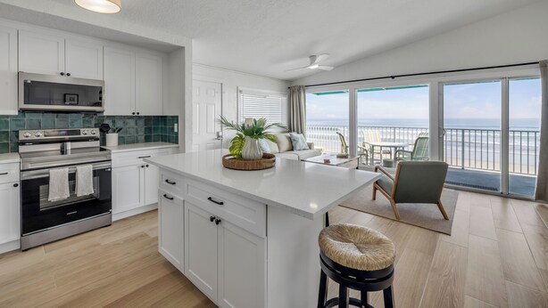 Cocina moderna con armarios blancos, una isla grande y vistas al exterior.