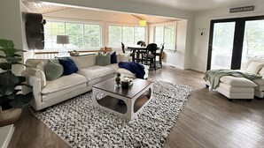 Ein geräumiges Wohnzimmer mit einem weißen Sofa, einem Couchtisch und einem Essbereich mit Tisch und Stühlen.