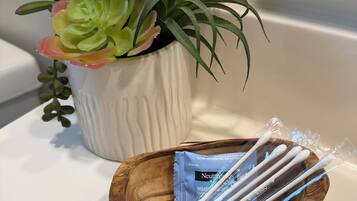 A white ceramic pot with a succulent plant and a wooden tray with dental hygiene products.