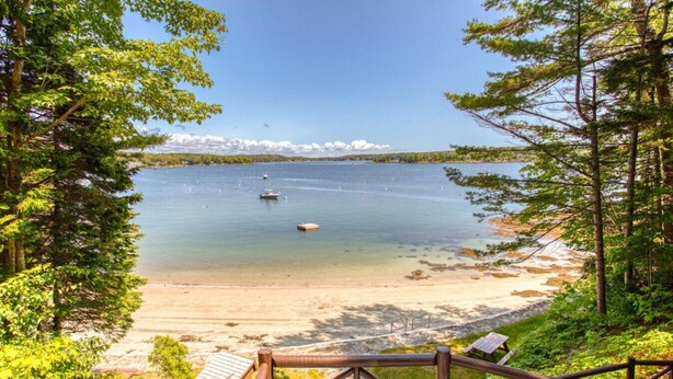 A beach with a wooden deck and a view of the lake.