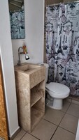 Een badkamer met een marmeren wastafel, toilet en een douchegordijn met Parijse motieven.