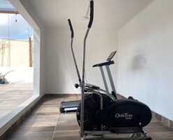 Een OrbiTrac Pro elliptische machine in een ruimte met een betegelde vloer en een groot raam.