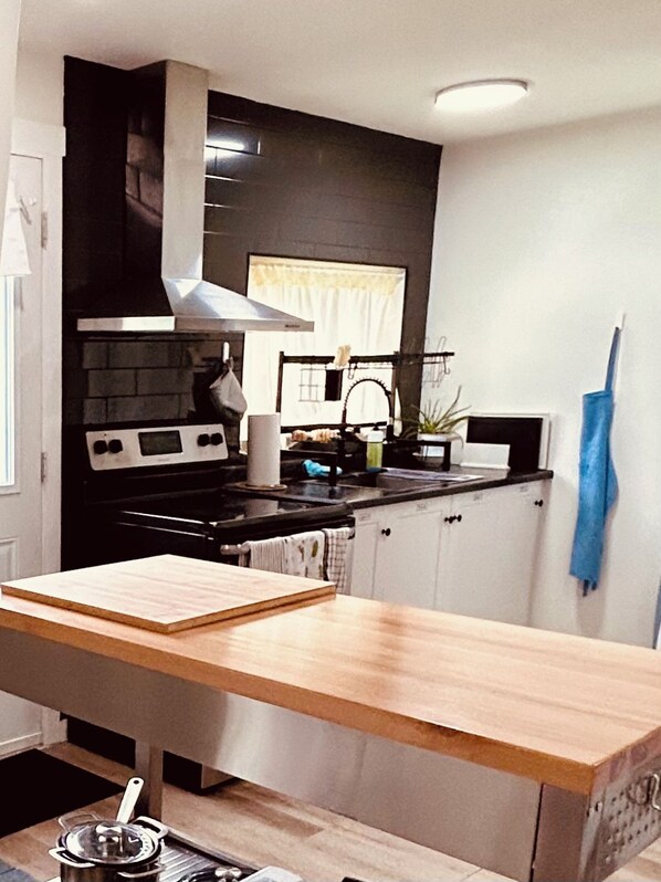 A kitchen with a wooden table, a stove, and cabinets.