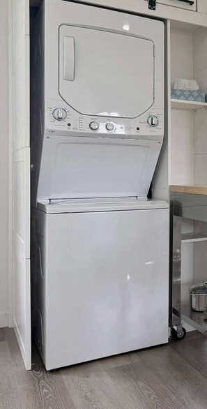 A compact, white, wall-mounted washer and dryer unit with a control panel featuring multiple settings. - Coastal Charm Meets Country Calm | Relaxing Cottage with Water Views & Hot Tub (Cocagne)