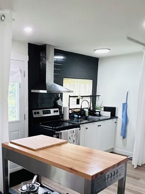 A modern kitchen with a black and white color scheme, stainless steel appliances, and a wooden table.