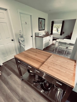 A compact kitchen with a wooden countertop, built-in appliances, and a dining area with a white table and chairs.