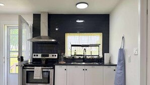 A modern kitchen with a black backsplash, stainless steel appliances, and white cabinetry.