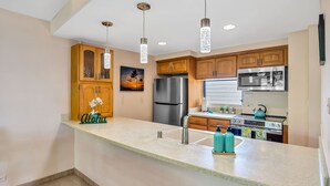 Una cocina moderna con armarios de madera, electrodomésticos de acero inoxidable e iluminación colgante.