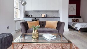 Ein modernes Wohnzimmer mit einem Glastisch, einem grauen Sofa und einer roten Akzentwand.