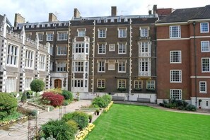 A multi-story building with a courtyard, featuring a well-maintained lawn and various plants. - 6VH Virginia House, 31 Bloomsbury Way by City Living London (London)