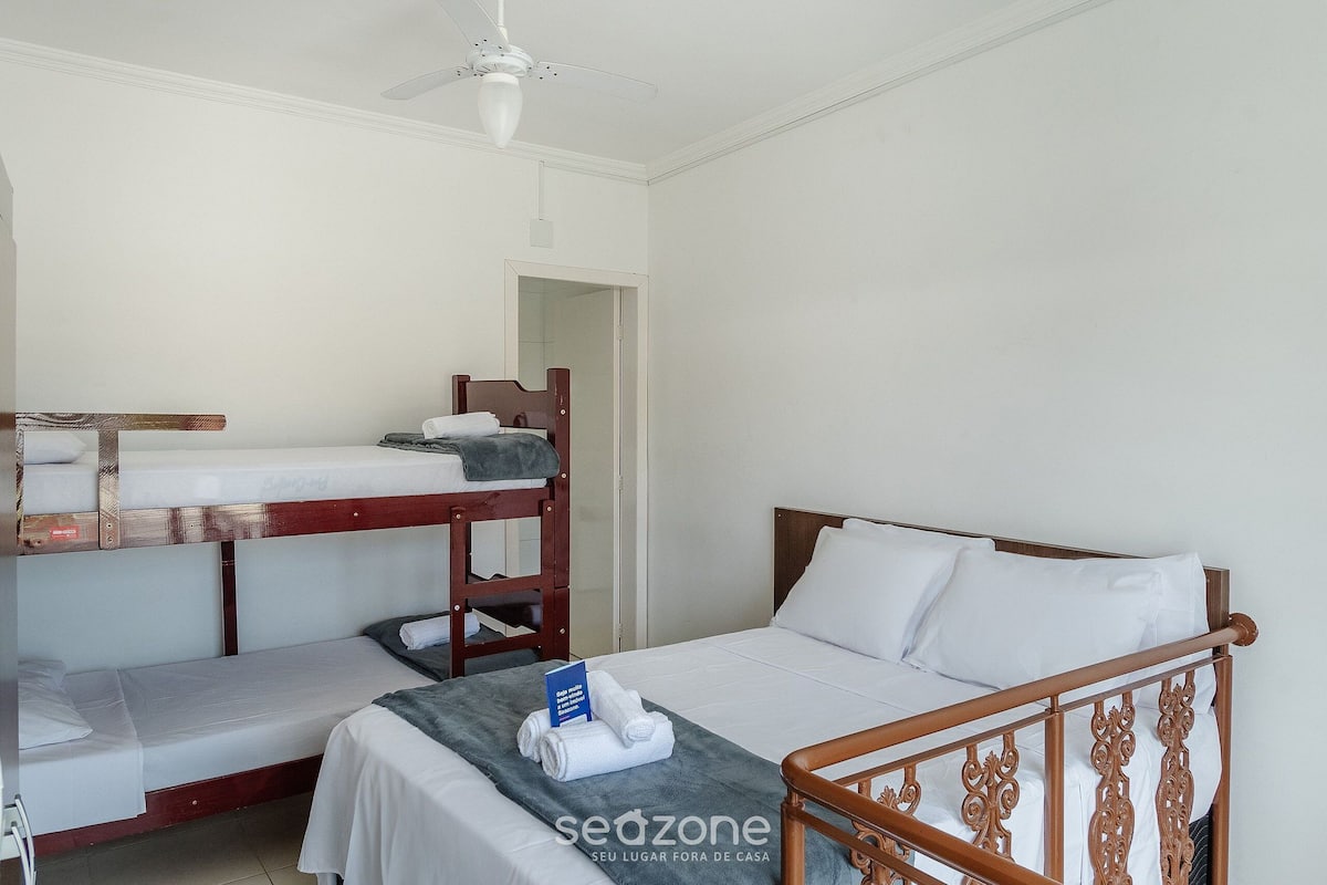 Ein Zimmer mit Etagenbetten, einem Einzelbett und einem Deckenventilator.