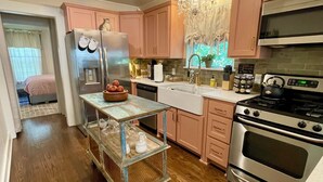 A kitchen with wooden flooring, stainless steel appliances, and pink cabinets. - Charming 3-bedroom cottage in Historic McKinney, three blocks from the square. (McKinney)