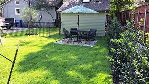 A backyard with a patio table and chairs, a small shed, and a wooden fence. - Charming 3-bedroom cottage in Historic McKinney, three blocks from the square. (McKinney)