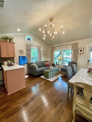 A spacious living area with a sofa, ottoman, and dining table. - Charming 3-bedroom cottage in Historic McKinney, three blocks from the square. (McKinney)