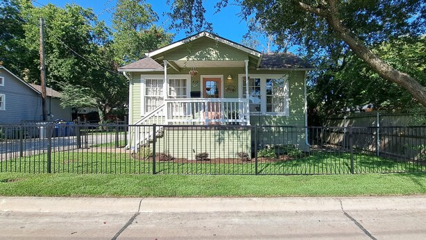 A two-story house with a porch, a fenced yard, and a street view. - Charming 3-bedroom cottage in Historic McKinney, three blocks from the square. (McKinney)