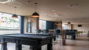 A billiards table, seating area, and large windows in a room. - Comfortable apartment for families with promotional price. (Olímpia)