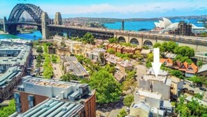 Eine Stadtansicht mit einer markanten Brücke, einer Uferpromenade und einem großen Opernhaus.
