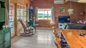A cozy cabin interior with a wooden interior, a dining table, a rocking chair, a sofa, and a television. - 3 bedroom beautiful home in Haderslev (Haderslev)