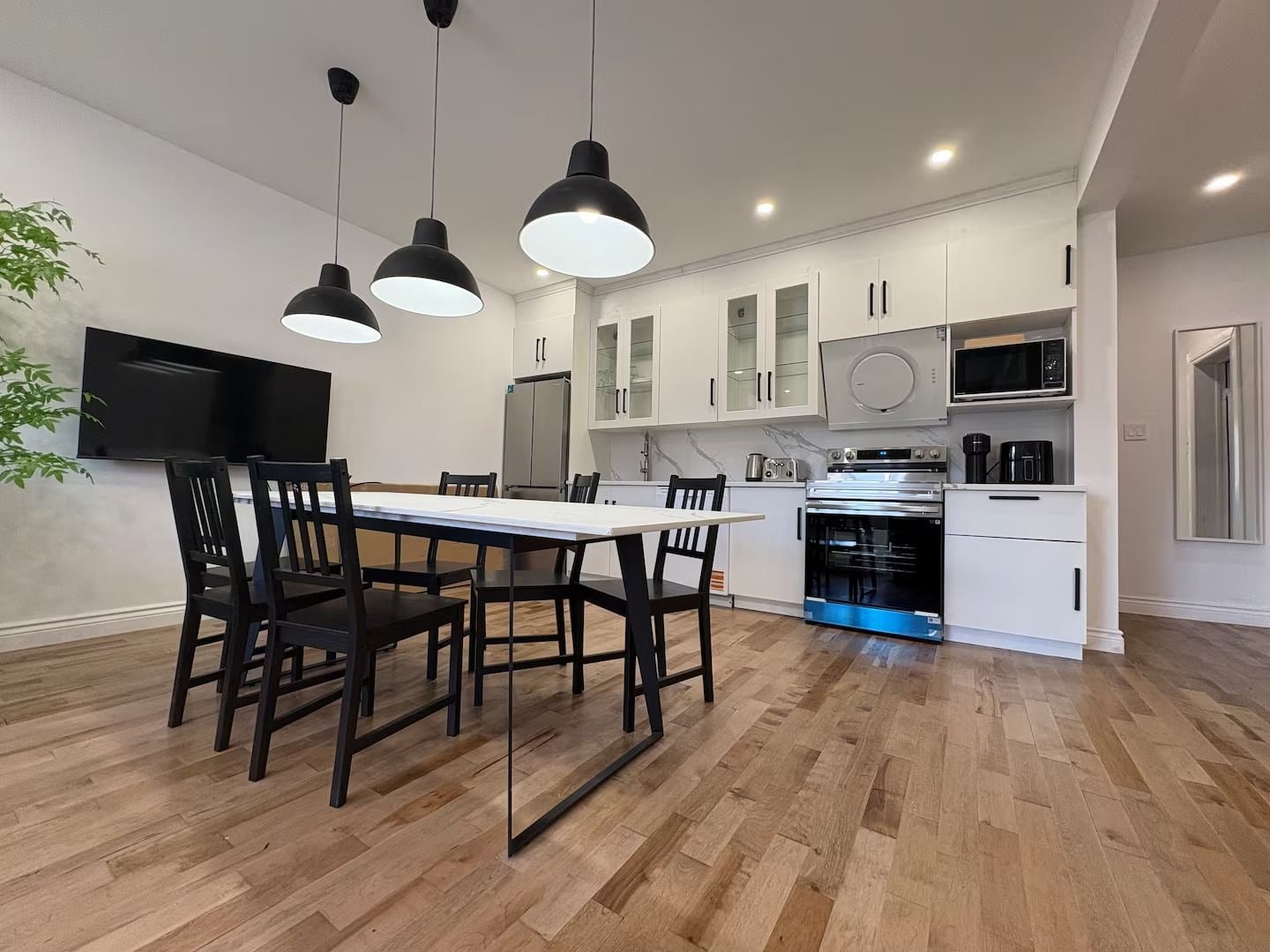 A modern kitchen with white cabinets, a dining table with chairs, and a built-in oven.