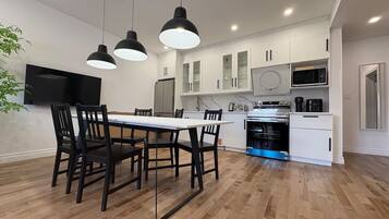 A modern kitchen with white cabinets, a dining table with chairs, and a built-in oven.