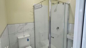 Ein Badezimmer mit Duschkabine, Toilette und Waschbecken.