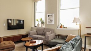 Ein Wohnzimmer mit Flachbildfernseher, zwei Sofas, einem Couchtisch und einer Lampe.