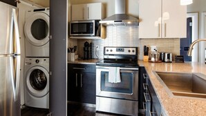 Eine moderne Küche mit Edelstahlgeräten, darunter eine Waschmaschine, eine Mikrowelle, ein Backofen und ein Spülbecken.