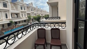 Un balcón con dos sillas, una piscina y una fila de casas adosadas al fondo.