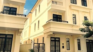 Un edificio de varios pisos con fachada simétrica, ventanas amplias y una entrada con reja.