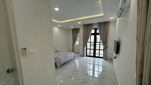Una habitación de hotel con cama, baño y un amplio ventanal con cortinas.