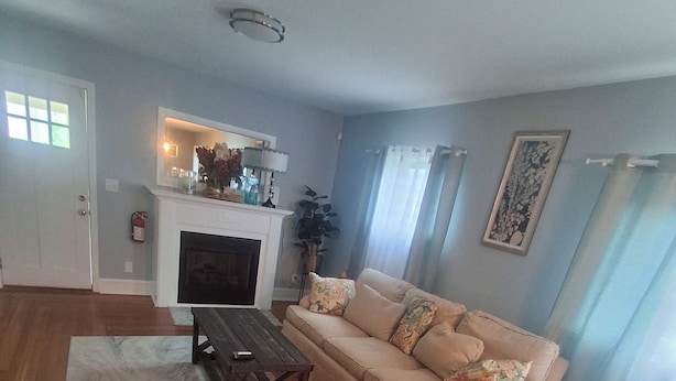 Una sala de estar con un sofá, una chimenea, un televisor y piso de madera.