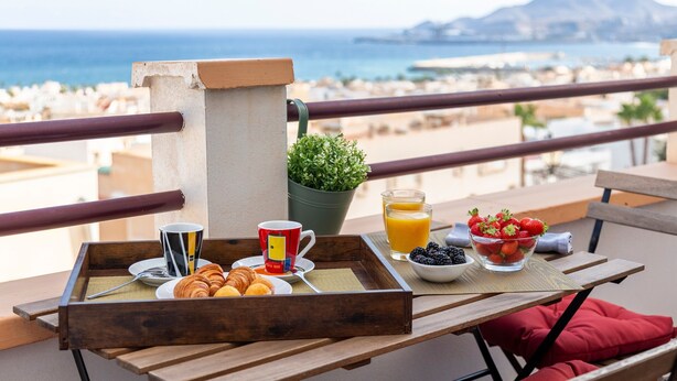 Ein Frühstückswagen auf einem Balkon mit Blick auf das Meer und die Berge.