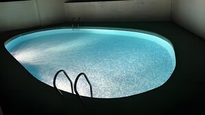 Ein Schwimmbecken mit zwei Leitern, umgeben von Mauern und Stufen.