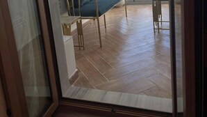 Um quarto com piso de madeira, uma cama e uma cadeira.