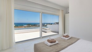 Un dormitorio con un amplio ventanal corredero que da a un balcón con vista al mar.