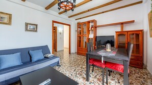 A living room with a sofa, a dining table, and a TV. - Holiday Home 'Mirador De Sorbas' with Balcony and Air Conditioning (Carboneras)