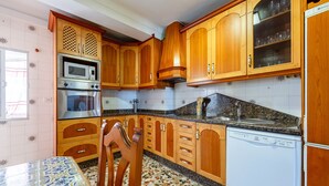 A kitchen with wooden cabinets, a microwave, oven, and dishwasher. - Holiday Home 'Mirador De Sorbas' with Balcony and Air Conditioning (Carboneras)