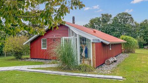A red wooden house with a sloped roof, a glass door, and a small porch. - Awesome home in Humble with WiFi (Humble)