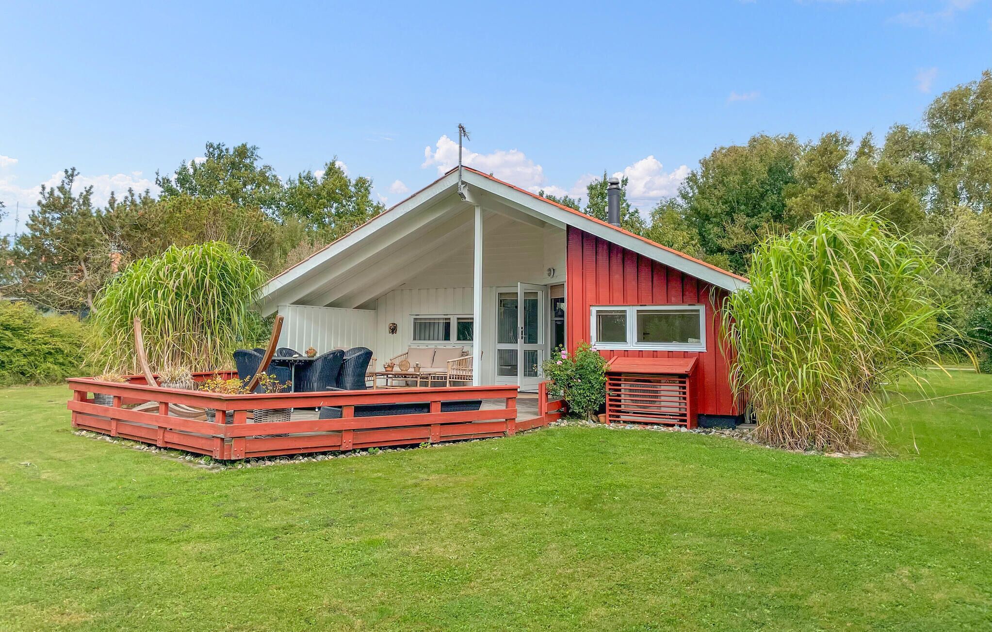 A red cabin with a covered porch, outdoor seating, and a small garden area.