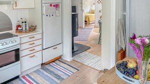 A modern kitchen with a stove, refrigerator, and wooden cabinets. There is a dining area with a table and chairs, and a bedroom visible in the background. - Awesome home in Humble with WiFi (Humble)
