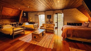 A cozy, rustic bedroom with wooden floors, a large bed, a sofa, and a small table.